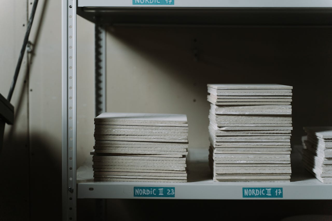 Stacks of ceramic tiles neatly arranged on industrial shelves in a dimly lit warehouse.